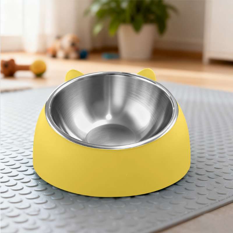 Yellow pet bowl with a metallic interior on a textured mat, with a blurred indoor background.