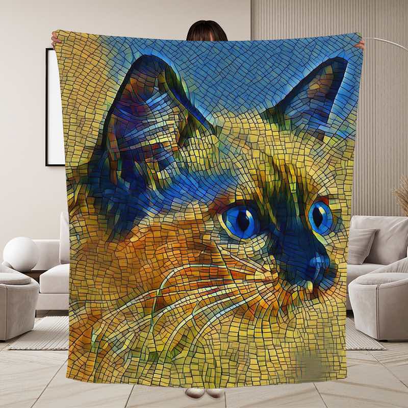 A large blanket or throw featuring a mosaic-style cat face in blue, yellow, orange, and brown tones, held by a person and shown in a living room setting.