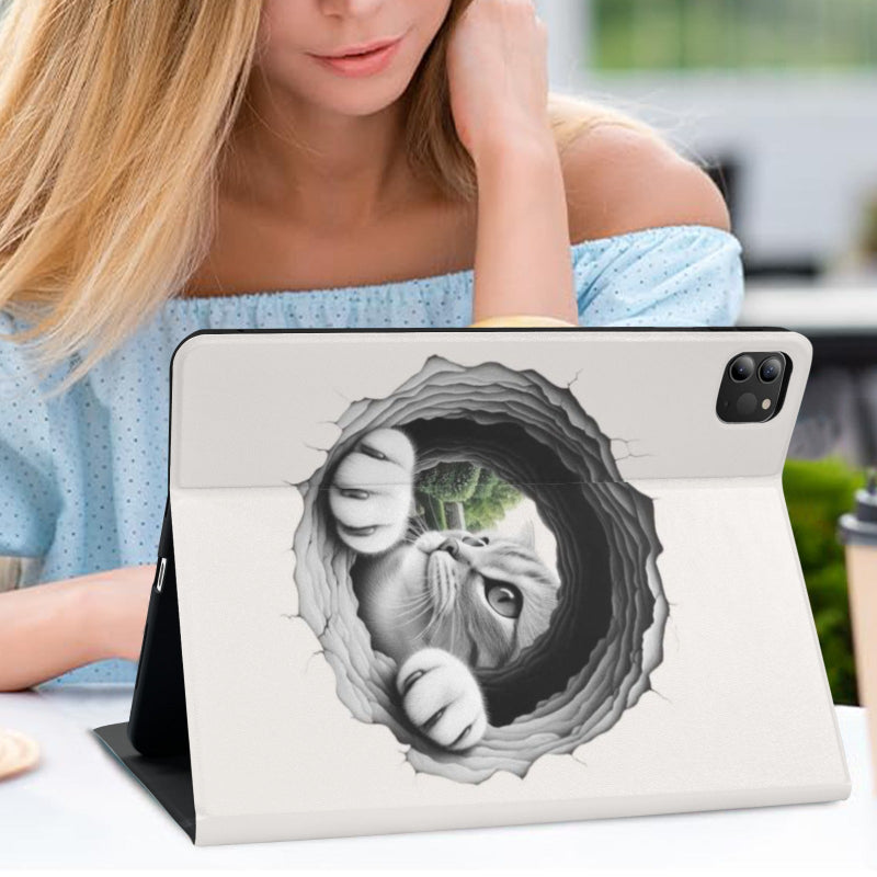 A tablet case with a 3D-effect cat hole graphic, shown on a tablet held in a person's hand at a desk.