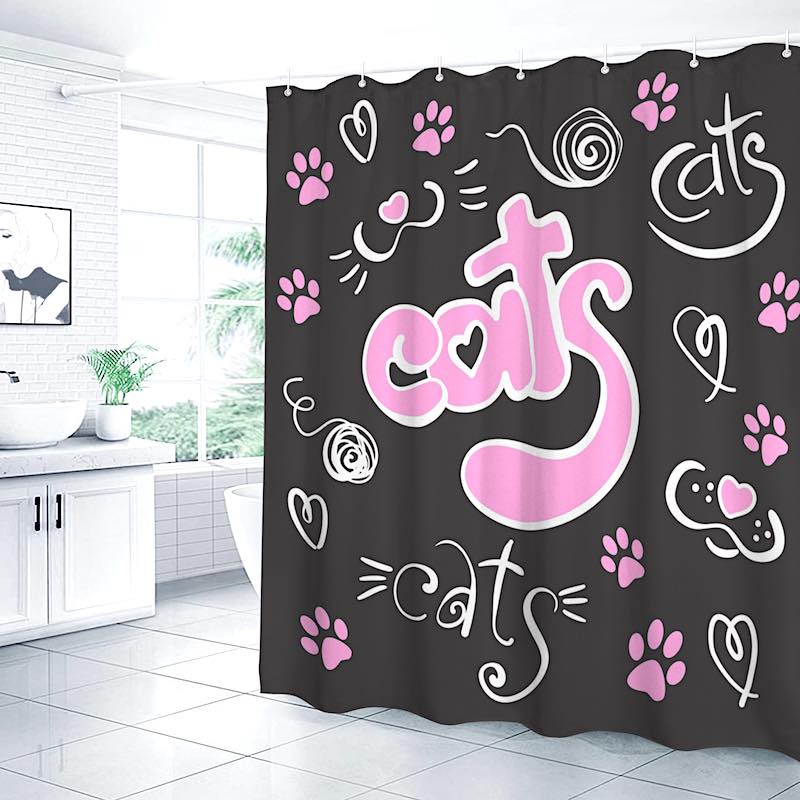 Black shower curtain with “cats” text and paw print designs in pink and white, displayed in a bathroom setting.
