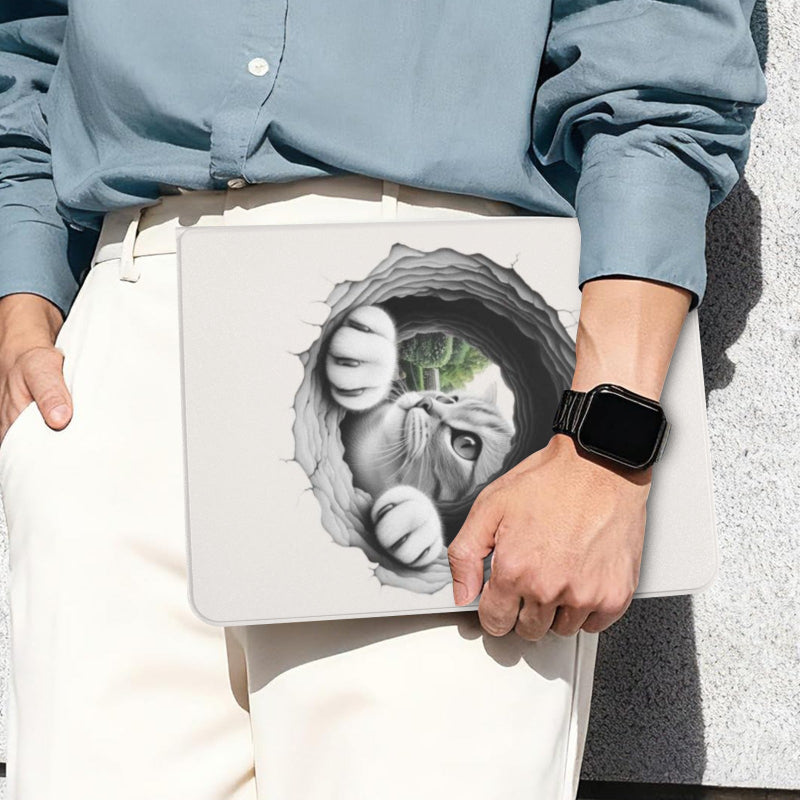 A person in a light blue button-up shirt and white pants holds a silver laptop with a 3D-effect graphic of a white cat bursting through a torn hole on the lid. The person is wearing a black smartwatch, standing against a gray textured wall.