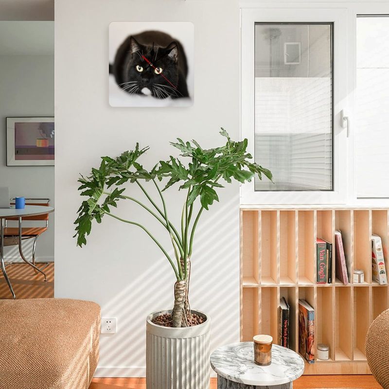Living room with a potted plant, bookshelf, and wall art of a black cat.